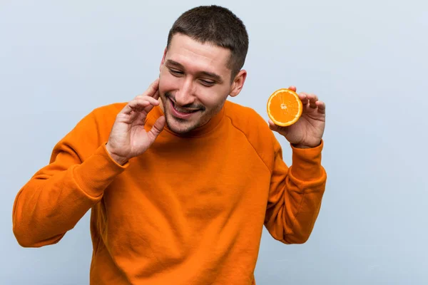 Joven Caucásico Sosteniendo Una Naranja Tratando Escuchar Chisme — Foto de Stock