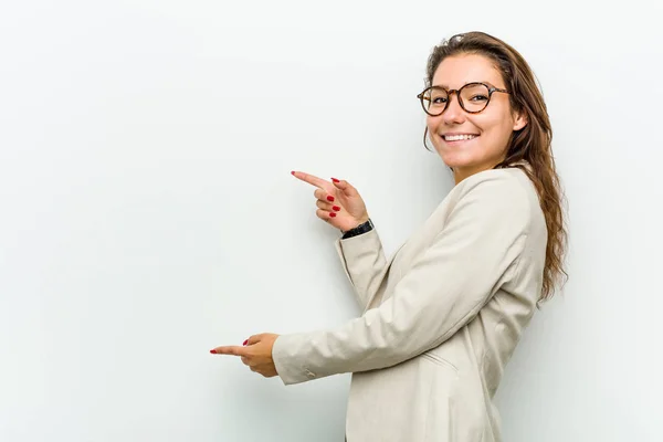 Young european business woman excited pointing with forefingers away.