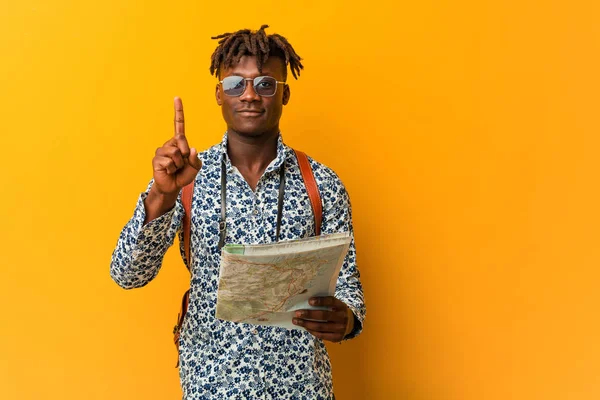 Young rasta black man holding a map showing number one with finger.