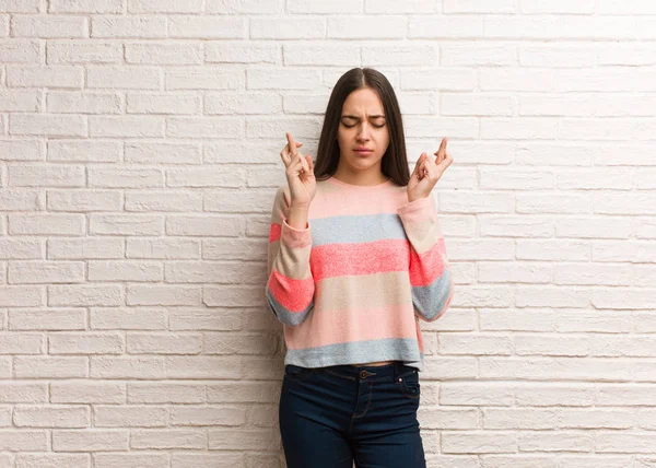 Young modern woman crossing fingers for having luck