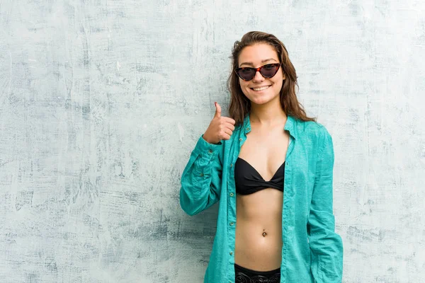 Young european woman wearing bikini smiling and raising thumb up