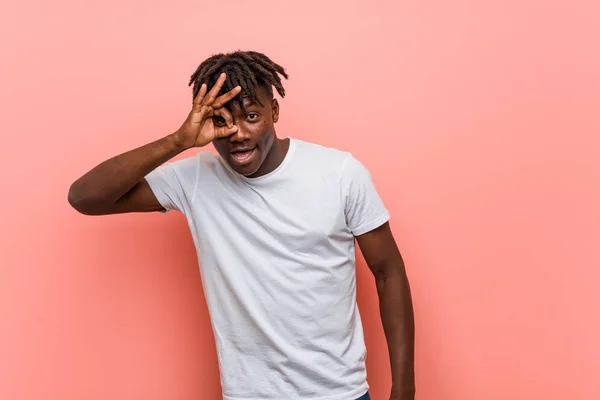 Young african black man excited keeping ok gesture on eye.