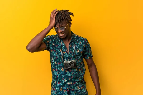 Young black rasta man wearing a vacation look forgetting something, slapping forehead with palm and closing eyes.