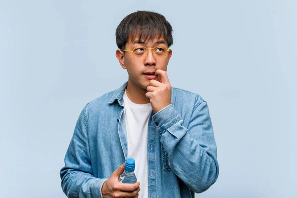 Junger Chinese Hält Eine Wasserflasche Der Hand Und Denkt Entspannt — Stockfoto