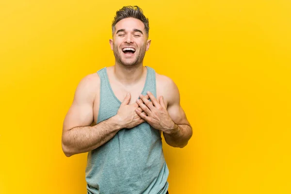 Jonge Fitnessman Tegen Een Gele Achtergrond Lachen Handen Het Hart — Stockfoto