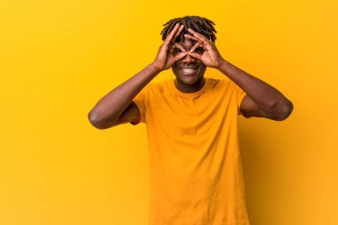 Sarı arka planda rastalar takan genç siyah adam gözlerde sorun olmadığını gösteriyor.