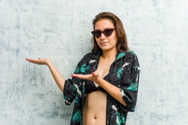 Bikini giyen genç Avrupalı kadın iki seçenek arasında şüphe ediyor.