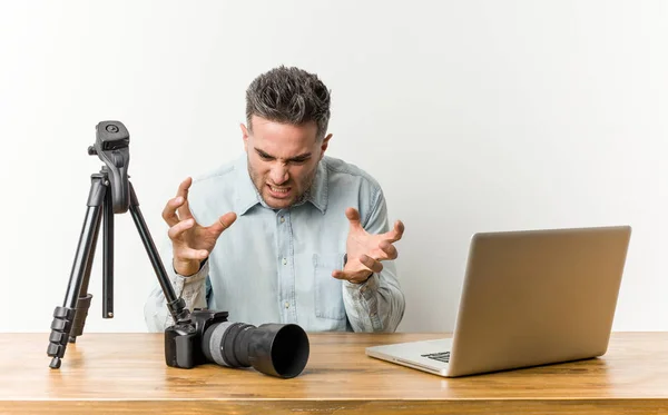 Young handsome photography teacher upset screaming with tense hands.