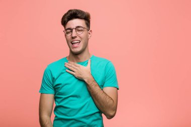 Genç, havalı, beyaz bir adam elini göğsünde tutarak kahkaha atıyor..