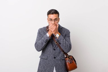 Beyaz bir duvara dayanmış genç Filipinli adam elleriyle ağzını kapatırken şok oldu..