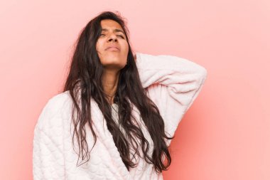 Pijama giyen genç Hintli bir kadın sabit yaşam tarzından dolayı boyun ağrısı çekiyor..