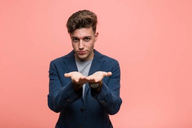 Genç iş adamı avuçlarıyla bir şey tutuyor ve kameraya sunuyor..