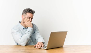 Dizüstü bilgisayarıyla çalışan genç ve yakışıklı bir adam. Sıkılmış, yorgun ve dinlenmeye ihtiyacı var..