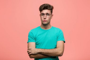 Genç, havalı, beyaz, mutsuz bir adam iğneleyici ifadesiyle kameraya bakıyor..