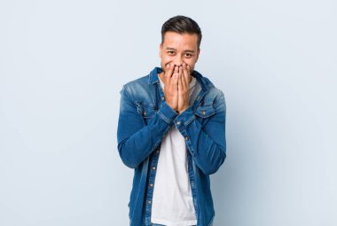 Filipinli yakışıklı bir adam bir şeye gülüyor, elleriyle ağzını kapatıyor..