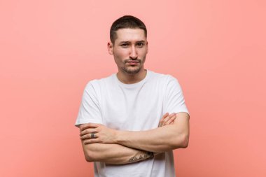 Genç ve sıradan bir adam kameraya alaycı bir ifadeyle bakıyor..