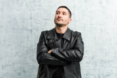 Genç rockçı adam kollarını kavuşturarak gülümsüyor..