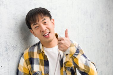 Genç Çinli adam yakından bakıp gülümsüyor ve parmağını kaldırıyor.