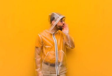 Yağmurluk giyen genç adam dedikodu fısıldıyor.