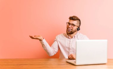 Çağrı merkezinde çalışan genç bir adam bir avuç içinde fotokopi alanı gösteriyor ve başka bir eli belinde tutuyor..