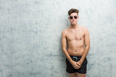 Mayo giyen genç beyaz adam şaşkın, kuşkulu ve güvensiz hissediyor..