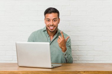 Genç Filipinli adam dizüstü bilgisayarıyla oturmuş seni işaret ediyor sanki seni davet ediyormuş gibi..