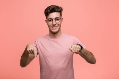 Genç, havalı, beyaz bir adam parmaklarıyla aşağıya bakıyor, olumlu bir duygu..