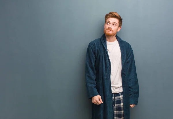 Young redhead man in pajama dreaming of achieving goals and purposes