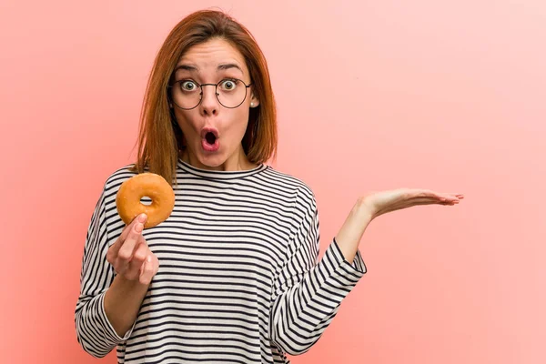 Mujer Joven Sosteniendo Donut Impresionado Sosteniendo Espacio Copia Palma —  Fotos de Stock