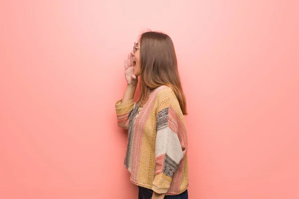 Young hippie woman on pink background whispering gossip undertone
