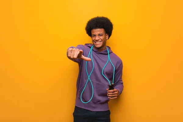 Young african american sport man holding a jump rope cheerful and smiling pointing to front