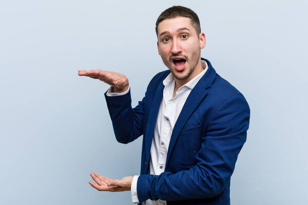 Молодой кавказский бизнесмен шокирован и поражен, держа в руках копировальное пространство
.