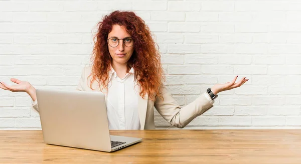 Молодая Рыжая Кудрявая Женщина Работающая Ноутбуком Приветственным Выражением Лица — стоковое фото