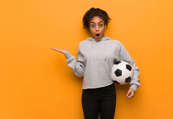 ヤシの手に何かを持っている若いフィットネス黒人女性 サッカーボールの保持 — ストック写真