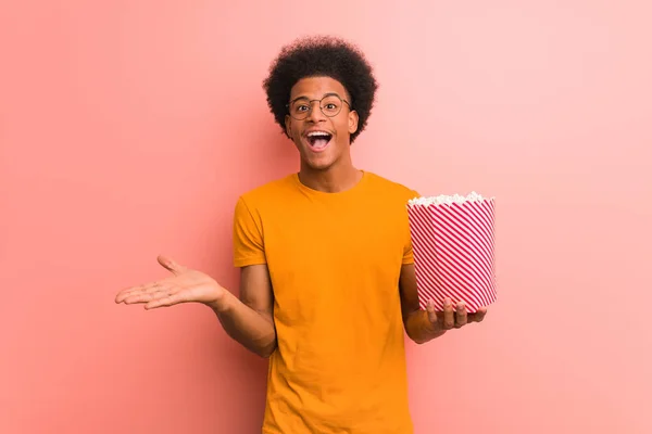 Young African American Holding Popcorn Bucket Celebrating Victory Success — Stock fotografie