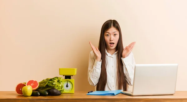 Młoda Chińska Dietetyczka Pracująca Laptopem Zaskoczona Zszokowana — Zdjęcie stockowe