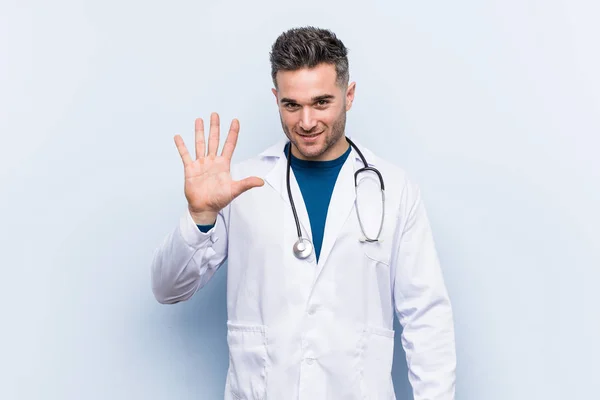 Genç Yakışıklı Doktor Gülümseyerek Beş Numarayı Parmaklarıyla Gösteriyor — Stok fotoğraf