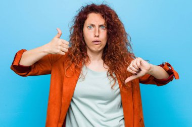 Genç, kızıl saçlı, zarif bir kadın, baş parmağını kaldırıyor, zor seçim konsepti.