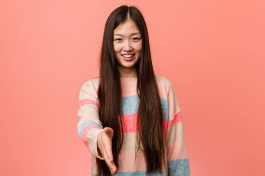 Genç, havalı Çinli kadın kameraya elini uzatıp selam veriyor..