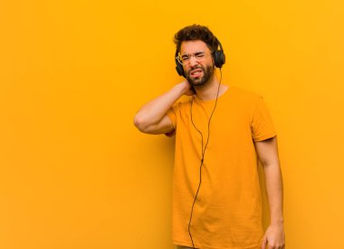 Genç adam müzik dinliyor, boyun ağrısı çekiyor.