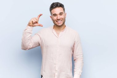 Genç yakışıklı, havalı adam parmakları olan, gülümseyen ve kendinden emin bir şey tutuyor..