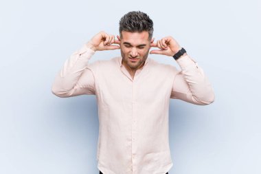 Genç yakışıklı havalı adam kulaklarını elleriyle kapatıyor..
