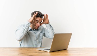 Genç ve yakışıklı bir adam dizüstü bilgisayarıyla çalışıyor. Başarı fırsatı bulmak için gözlerini açık tutuyor..