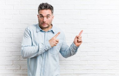 Duvara yaslanmış genç yakışıklı bir adam işaret parmağıyla bir fotokopi alanını işaret ederek şok oldu..