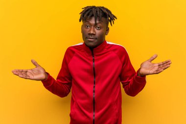 Genç fitness Afrikalı bir adam sorgulama jesti için omuzlarını silkiyor..