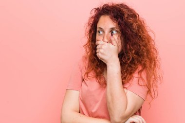 Genç, doğal ve otantik kızıl saçlı kadın. Düşünceli bir şekilde fotokopi odasına bakıyor. Ağzını eliyle kapatıyor..