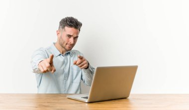 Genç yakışıklı adam dizüstü bilgisayarıyla çalışıyor. Neşeli gülümsemeler öne bakıyor..