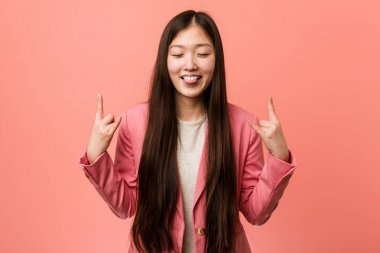 Pembe takım elbiseli genç Çinli kadın parmaklarıyla taş hareketi yapıyor.