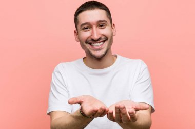 Avuçlarıyla bir şey tutan, kameraya sunan sıradan bir genç..