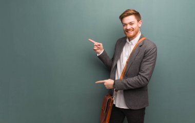 Genç kızıl saçlı iş adamı parmağıyla kenarı işaret ediyor.